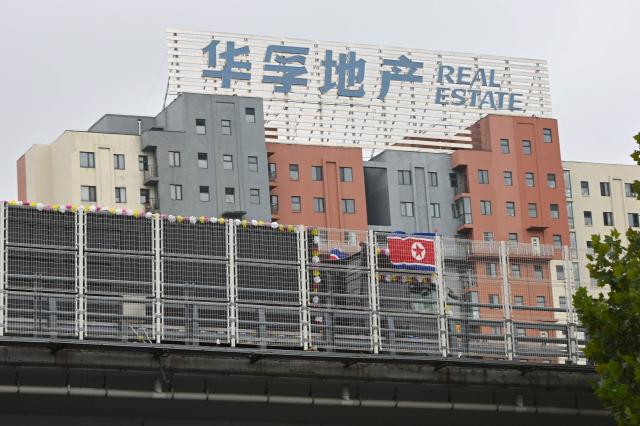A truck bearing a North Korean flag crosses the new cross-border bridge linking China and North Korea in Dandong, Liaoning Province, on October 15, 2026. A new four-lane road bridge linking China and North Korea finally opened on October 15, 12 years late, enabling the Asian giant and its isolated nuclear-armed neighbour to step up cross-border trade substantially. (Photo by Michael ZHANG / AFP)