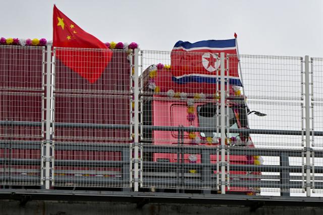 A truck bearing a North Korean flag crosses the new cross-border bridge linking China and North Korea in Dandong, Liaoning Province, on October 15, 2026. A new four-lane road bridge linking China and North Korea finally opened on October 15, 12 years late, enabling the Asian giant and its isolated nuclear-armed neighbour to step up cross-border trade substantially. (Photo by Michael ZHANG / AFP)