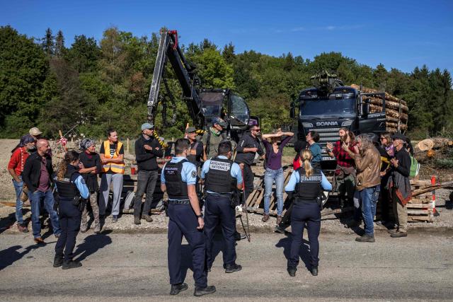 Police officers intervene as protesters block a truck carrying logs during the controversial construction of the A412 motorway, near Perrignier, Haute-Savoie, France, on October 14, 2026. A coalition of associations, farmers, and residents on October 14, 2026, sought to halt construction of the A412 motorway, arguing that its environmental impact runs “counter to the climate emergency.” While a court ruling is expected on October 15, 2026, protesters have staged near-daily demonstrations, resulting in dozens of detentions and fines, according to organizers. (Photo by Fabrice COFFRINI / AFP)
