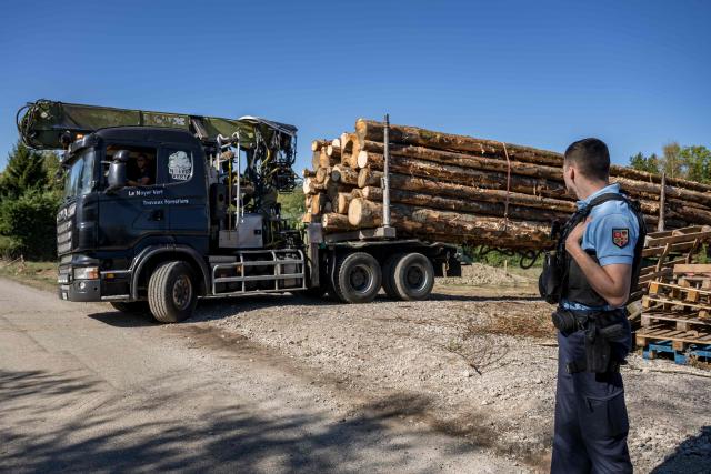 A police officer secures the departure of a truck transporting logs during the controversial construction of the A412 motorway, near Perrignier, Haute-Savoie, France, on October 14, 2026. A coalition of associations, farmers, and residents on October 14, 2026, sought to halt construction of the A412 motorway, arguing that its environmental impact runs “counter to the climate emergency.” While a court ruling is expected on October 15, 2026, protesters have staged near-daily demonstrations, resulting in dozens of detentions and fines, according to organizers. (Photo by Fabrice COFFRINI / AFP)