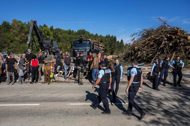 Police officers intervene as protesters block a truck carrying logs during the controversial construction of the A412 motorway, near Perrignier, Haute-Savoie, France, on October 14, 2026. A coalition of associations, farmers, and residents on October 14, 2026, sought to halt construction of the A412 motorway, arguing that its environmental impact runs “counter to the climate emergency.” While a court ruling is expected on October 15, 2026, protesters have staged near-daily demonstrations, resulting in dozens of detentions and fines, according to organizers. (Photo by Fabrice COFFRINI / AFP)