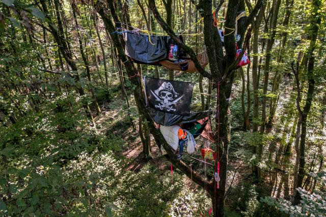 This photograph shows activists known as the "squirrels" perched in trees to prevent the trees from being cut down during the controversial construction of the A412 motorway, in a forest near Perrignier, Haute-Savoie, France, on October 14, 2026. A coalition of associations, farmers, and residents on October 14, 2026, sought to halt construction of the A412 motorway, arguing that its environmental impact runs “counter to the climate emergency.” While a court ruling is expected on October 15, 2026, protesters have staged near-daily demonstrations, resulting in dozens of detentions and fines, according to organizers. (Photo by Fabrice COFFRINI / AFP)