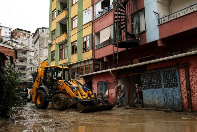 People use shovels to clean water that entered their shops while a backhoe loader clears mud that has formed on the road after a flood in the Ayazaga district in Istanbul on October 15, 2026. Istanbul was on October 15, 2026 battling to recover from flooding caused by what officials said was the heaviest rainfall in the city since records began more than 80 years ago, as the downpour continued. The rain began lashing Turkey's largest city in earnest on October 14, 2026 morning and intensified throughout the day, causing chaos and flash flooding, with footage showing cars being dragged away by the fast-flowing waters. (Photo by BERK OZKAN / AFP)