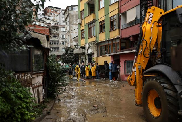People use shovels to clean water that entered their shops while a backhoe loader clears mud that has formed on the road after a flood in the Ayazaga district in Istanbul on October 15, 2026. Istanbul was on October 15, 2026 battling to recover from flooding caused by what officials said was the heaviest rainfall in the city since records began more than 80 years ago, as the downpour continued. The rain began lashing Turkey's largest city in earnest on October 14, 2026 morning and intensified throughout the day, causing chaos and flash flooding, with footage showing cars being dragged away by the fast-flowing waters. (Photo by BERK OZKAN / AFP)