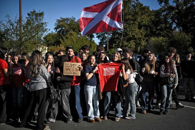 High school students gather outside the Graves high school, one holding a T-shirt reading "Macron takes us for idiots", as the Education Minister visits amid a nationwide high school student protest movement over learning conditions in Gradignan, a Bordeaux suburb, on October 15, 2026. Replacement problems in the 114 high schools classified as priority by the National Education Ministry will be resolved when classes resume after the All Saints' Day holidays, Education Minister Edouard Geffray said on October 15, 2026 during a visit to the Gironde department. (Photo by Christophe ARCHAMBAULT / AFP)