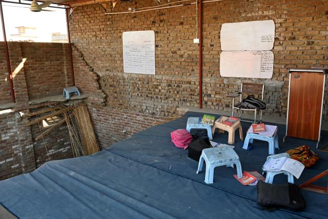 A collapsed section of a class as students' belongings lie around following a roof collapse of a school in Peshawar on October 15, 2026. The roof of a school collapsed in Pakistan's northwestern city of Peshawar, killing a teacher and 32 students, mostly aged under 14, health officials said on October 15, as residents and rescuers scrambled to pull children from the rubble. (Photo by Abdul MAJEED / AFP)