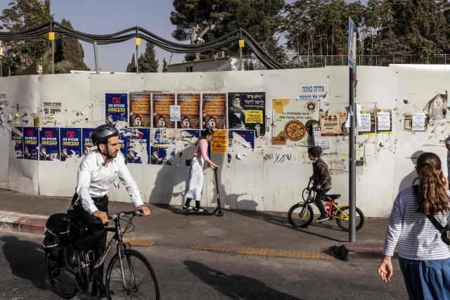 Orthodox Jews pass election campaign posters for the ultra-Orthodox Jewish party Shas in Jerusalem on October 15, 2026. Israel heads to the polls on October 27 in its first election since the October 7, 2023 Hamas-led attack, in what is seen as a referendum on the prime minister. (Photo by JOHN WESSELS / AFP)