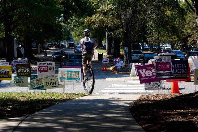 A voter rides away on a unicycle after casting their ballot at the NC State University Business Services building on the first day of early voting in Raleigh, North Carolina on October 15, 2026. Americans voting in the November 3 midterm elections will decide who controls Congress for the final two years of Donald Trump's presidency, along with dozens of governorships and thousands of state offices. (Photo by Matt RAMEY / AFP)