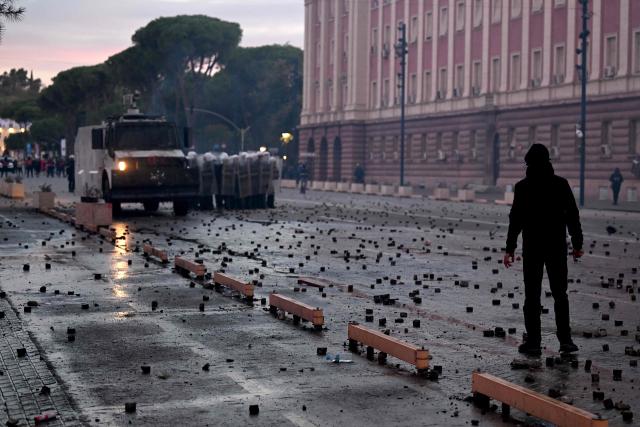 A protester confronts the riot police during an anti-government demonstration in central Tirana on October 15, 2026, as protests continued for a third consecutive day over university conditions and demands for the resignation of Albanian Prime Minister Edi Rama. The latest rally follows two nights of violence in the capital, during which protesters and riot police clashed, police used water cannons and tear gas, and demonstrators damaged government offices and shops and set fire to several buildings. (Photo by Armend NIMANI / AFP)