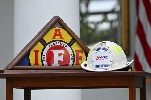 A flag from the The International Association of Fire Fighters (IAFF) and National Volunteer Fire Council (NVFC) hat rests on a table as US President Donald Trump speaks in the Rose Garden at the White House, Washington DC, October 15, 2026. (Photo by Jim WATSON / AFP)