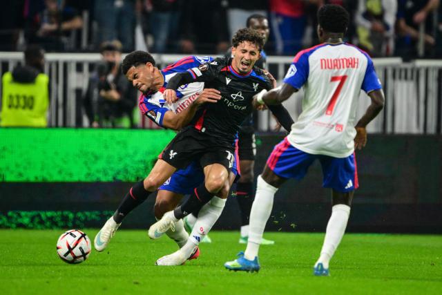 Lyon's Swiss defender #13 Zachary Athekame (L) vies with Crystal Palace's English forward Dwight McNeil (C) during the UEFA Europa League, league phase matchday 2, football match between Olympique Lyonnais and Crystal Palace at the Groupama Stadium in Decines-Charpieu, near Lyon, on October 15, 2026. (Photo by OLIVIER CHASSIGNOLE / AFP)