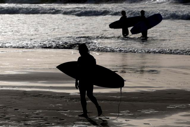 Israeli surfers stands on the water’s edge at sunset along the shores of the coastal city of Tel Aviv, on October 15, 2026. (Photo by JACK GUEZ / AFP)