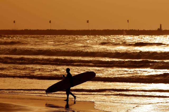 An Israeli surfer exists the water at sunset along the shores of the coastal city of Tel Aviv, on October 15, 2026. (Photo by JACK GUEZ / AFP)