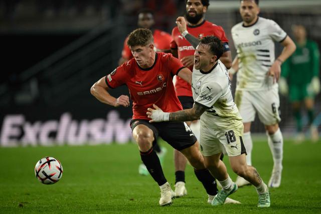 OFI Crete's forward #18 Thiago Nuss (R) falls from a challenge from Rennes' English defender #04 Charlie Cresswell (C) during the UEFA Europa League, league phase matchday 2, football match between Stade Rennais and OFI Crete at the Roazhon Park in Rennes, western France on October 15, 2026. (Photo by Loic VENANCE / AFP)