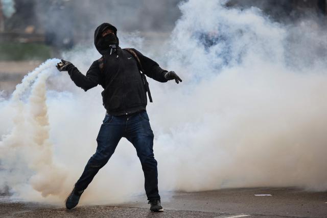 A man throws tear gas during a demonstration demanding that the government of Argentine President Javier Milei comply with a law updating funding for public universities, in Buenos Aires, on October 15, 2026. (Photo by Emiliano Lasalvia / AFP)