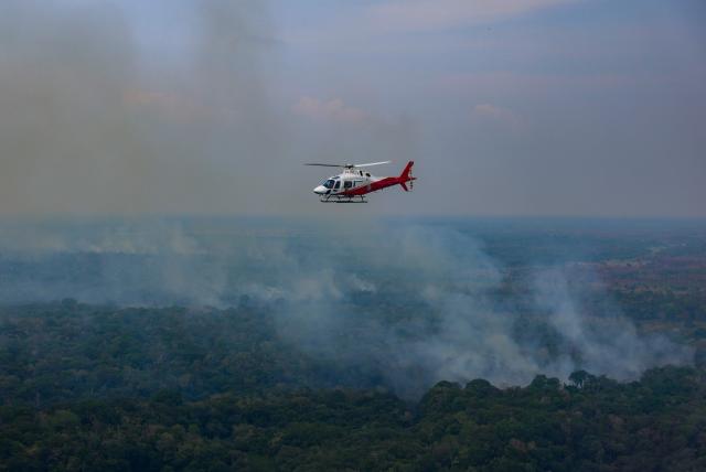 An IBAMA helicopter is seen flying over an area affected by fires in the Amazon rainforest in Autazes, in the state of Amazonas, northern Brazil on October 15, 2026. (Photo by MICHAEL DANTAS / AFP)
