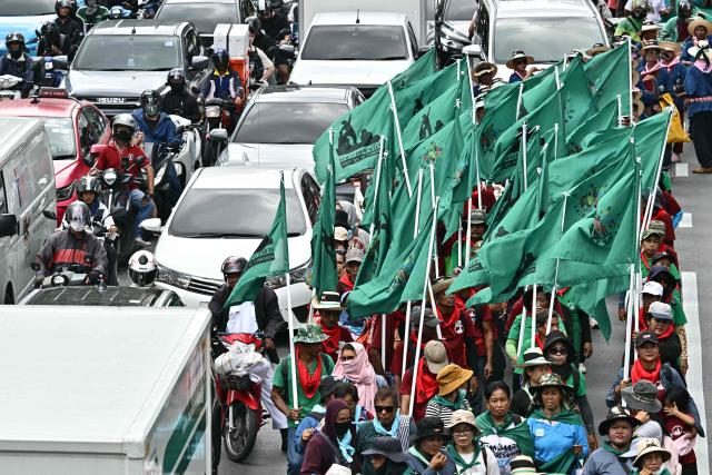 Demonstrators march next to motorists on a road during a protest against the International Monetary Fund (IMF) and World Bank Group in Bangkok on October 16, 2026, as the IMF Annual Meetings take place in the Thai capital. (Photo by ANTHONY WALLACE / AFP)