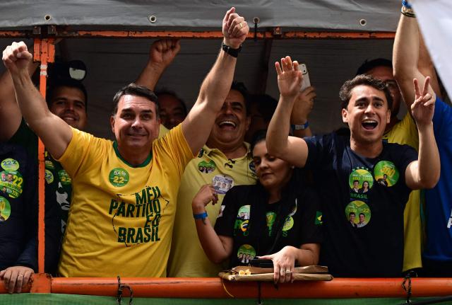 (FILES) Brazilian right-wing presidential candidate Flavio Bolsonaro, gestures to supporters next to deputy Nikolas Ferreira during a campaign rally in Juiz de Fora, Minas Gerais state, Brazil on September 9, 2026. Flavio Bolsonaro has campaigned as a more moderate figure than his father, who had a history of racist, misogynistic and homophobic outbursts. While the younger Bolsonaro has railed about "gender ideology" he is generally seen as more tolerant than the influencers trying to get the vote out for him. (Photo by Pablo PORCIUNCULA / AFP)