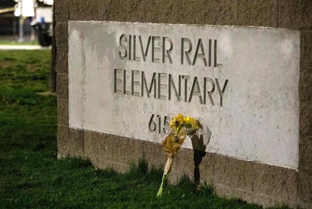 A flower bouquet rests against the sign outside the Silver Rail Elementary School following a shooting in Bend, Oregon, on October 15, 2026. Three children and one teacher were shot dead at an elementary school Thursday in the northwestern US state of Oregon, police said, adding that the assailant was a 16-year-old who was killed by an armed bystander. (Photo by Payton Bruni / AFP)