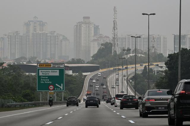 Motorists drive on a highway as buildings are seen covered in haze in Kuala Lumpur on October 16, 2026, as the country continues to be shrouded in haze caused by fires in Indonesia. Toxic haze has covered parts of Indonesia, Malaysia and Singapore for weeks as Jakarta struggles to contain fires that have scorched large tracts of Borneo and Sumatra, with the smoke drifting across the region. (Photo by Jam STA ROSA / AFP)