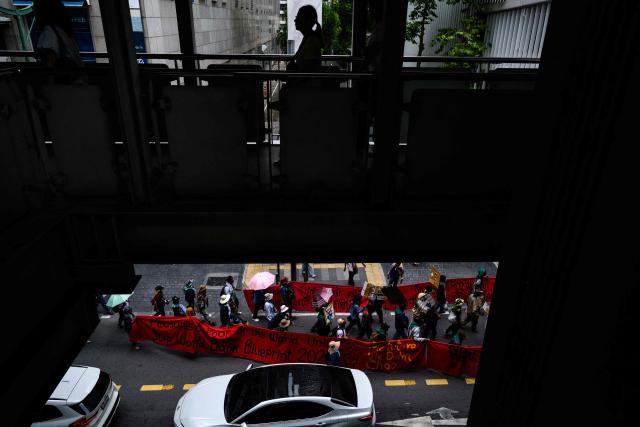 Demonstrators (bottom) march below a footbridge during a protest against the International Monetary Fund (IMF) and World Bank Group in Bangkok on October 16, 2026, as the IMF Annual Meetings take place in the Thai capital. (Photo by ANTHONY WALLACE / AFP)