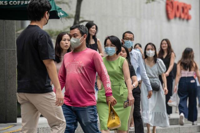 People wearing face masks walk throuhg the business district in Singapore on October 16, 2026, as the country continues to be shrouded in haze caused by fires in Indonesia. Toxic haze has covered parts of Indonesia, Malaysia and Singapore for weeks as Jakarta struggles to contain fires that have scorched large tracts of Borneo and Sumatra, with the smoke drifting across the region. (Photo by Yuichi YAMAZAKI / AFP)