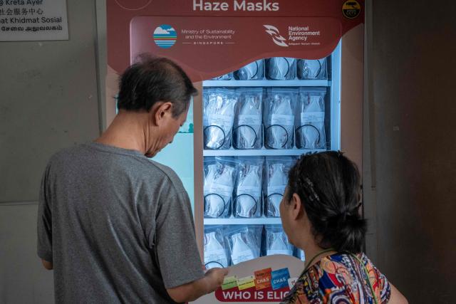 People use an N95 face mask vending machine in Singapore on October 16, 2026, as the country continues to be shrouded in haze caused by fires in Indonesia. Toxic haze has covered parts of Indonesia, Malaysia and Singapore for weeks as Jakarta struggles to contain fires that have scorched large tracts of Borneo and Sumatra, with the smoke drifting across the region. (Photo by Yuichi YAMAZAKI / AFP)