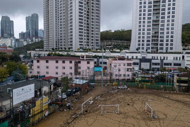 This aerial photograph shows a football pitch covered with mud and debris, with apartment towers in the background, two days after flooding caused by what officials said was the heaviest rainfall in the city since records began more than 80 years ago, in the Ayazaga district of Istanbul on October 16, 2026. (Photo by Yasin AKGUL / AFP)