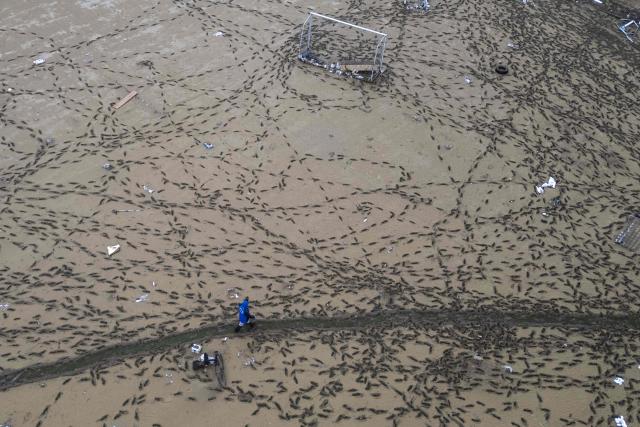 This aerial photograph shows a person walking through footprints in the mud covering a football pitch, two days after flooding caused by what officials said was the heaviest rainfall in the city since records began more than 80 years ago, in the Ayazaga district of Istanbul on October 16, 2026. (Photo by Yasin AKGUL / AFP)