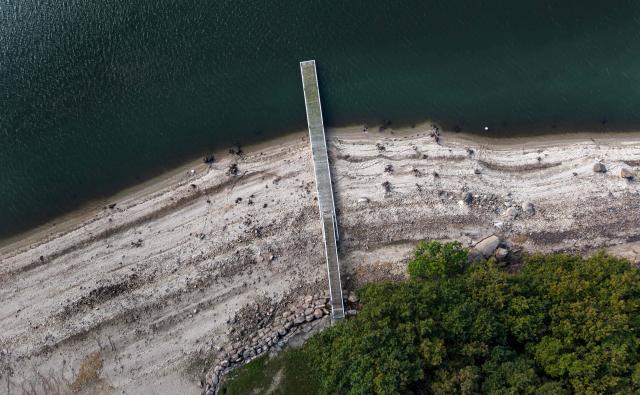 This aerial photograph shows a dock on Lake Drennec, where water levels have dropped due to drought, in Sizun, western France, on October 14, 2026. Water resources in the Brest area and across the Finistère department are under severe pressure due to a significant rainfall deficit. (Photo by Fred TANNEAU / AFP)