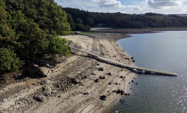 This aerial photograph shows a dock on Lake Drennec, where water levels have dropped due to drought, in Sizun, western France, on October 14, 2026. Water resources in the Brest area and across the Finistère department are under severe pressure due to a significant rainfall deficit. (Photo by Fred TANNEAU / AFP)