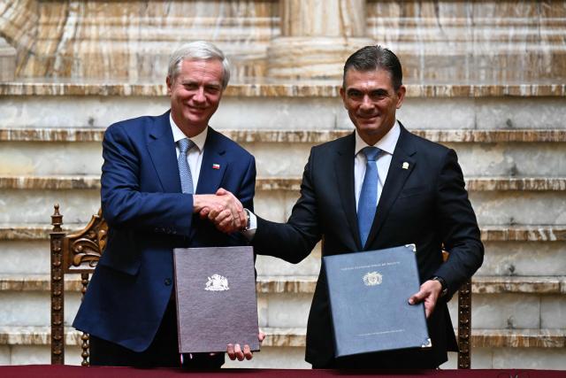 Chile's President Jose Antonio Kast (L) and Bolivia's President Rodrigo Paz shake hands while holding signed documents during a signing ceremony at the Palacio Quemado presidential palace in La Paz on October 16, 2026. (Photo by AIZAR RALDES / AFP)
