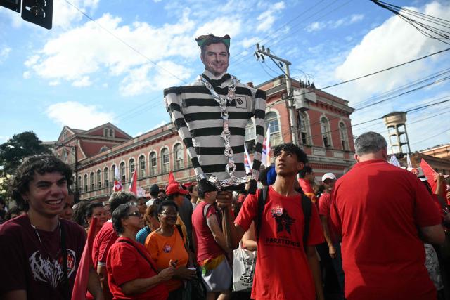 A supporter of Brazil's President and presidential candidate Luiz Inacio Lula da Silva of the Workers' Party (PT) holds a dummy of Flavio bolsonaro during a campaign rally in Juiz de Fora, Minas Gerais state, Brazil, on October 16, 2026, ahead of last round of the presidential runoff election. (Photo by MAURO PIMENTEL / AFP)
