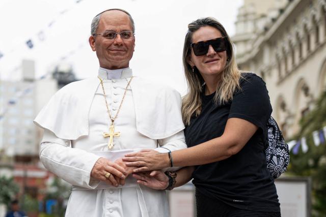 A woman poses for a photograph with a hyperrealistic silicone statue of Pope Leo XIV, created by Peruvian artist Walter Huaman, in Lima, Peru, on October 16, 2026. (Photo by ERNESTO BENAVIDES / AFP)