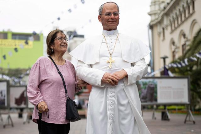 A woman poses for a photograph with a hyperrealistic silicone statue of Pope Leo XIV, created by Peruvian artist Walter Huamán, in Lima, Peru, on October 16, 2026. (Photo by ERNESTO BENAVIDES / AFP)
