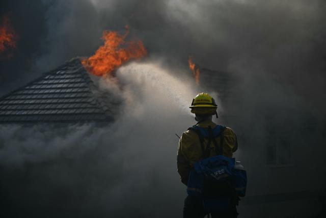 A firefighter battles the Norte Fire in San Juan Capistrano, California, on October 16, 2026. Evacuation orders have been issued for parts of Orange County. (Photo by Patrick T. Fallon / AFP)