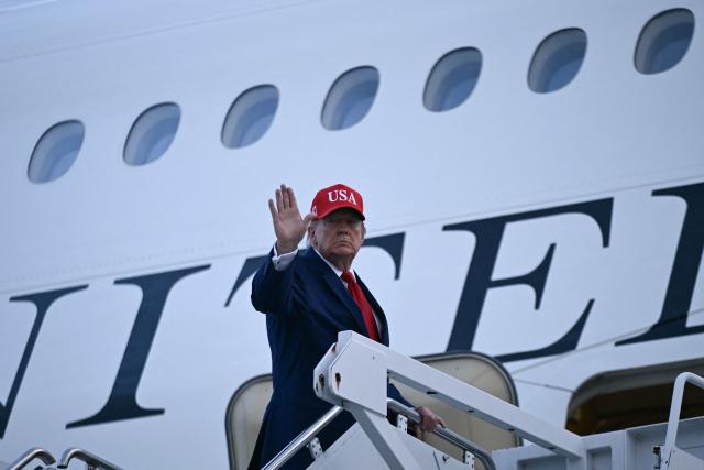 US President Donald Trump waves as he boards Air Force One at Dobbins Reserve Air Base in Marietta, Georgia, on October 16, 2026. Trump was campaigning for US Representative Mike Collins for US Senate and Rick Jackson for governor. (Photo by Brendan SMIALOWSKI / AFP)