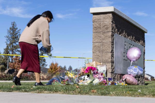 A woman places flowers at a vigil outside of Silver Rail Elementary School in Bend, Oregon, on October 16, 2026. Three children and one teacher were shot dead at an elementary school on October 15 in the northwestern US state of Oregon, police said, adding that the assailant was a 16-year-old who was killed by an armed bystander. (Photo by Payton Bruni / AFP)