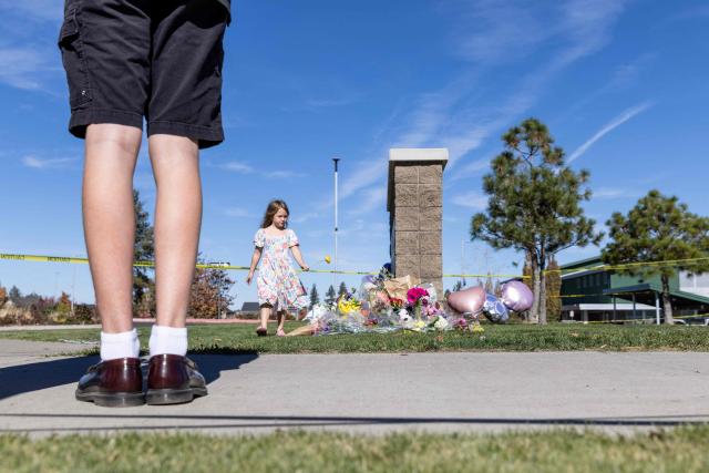 A young girl places a flower at a vigil outside of Silver Rail Elementary School in Bend, Oregon, on October 16, 2026. Three children and one teacher were shot dead at an elementary school on October 15 in the northwestern US state of Oregon, police said, adding that the assailant was a 16-year-old who was killed by an armed bystander. (Photo by Payton Bruni / AFP)