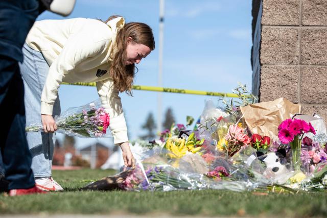 A Bend resident and student teacher places flowers at a vigil outside of Silver Rail Elementary School in Bend, Oregon, on October 16, 2026. Three children and one teacher were shot dead at an elementary school on October 15 in the northwestern US state of Oregon, police said, adding that the assailant was a 16-year-old who was killed by an armed bystander. (Photo by Payton Bruni / AFP)