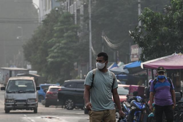 People wear masks in Kuala Lumpur on October 17, 2026, as the country continues to be shrouded in haze caused by fires in Indonesia. The blazes in Indonesia have closed schools and fuelled a surge of respiratory complaints and growing frustration about the inability to contain the situation. (Photo by Jam STA ROSA / AFP)