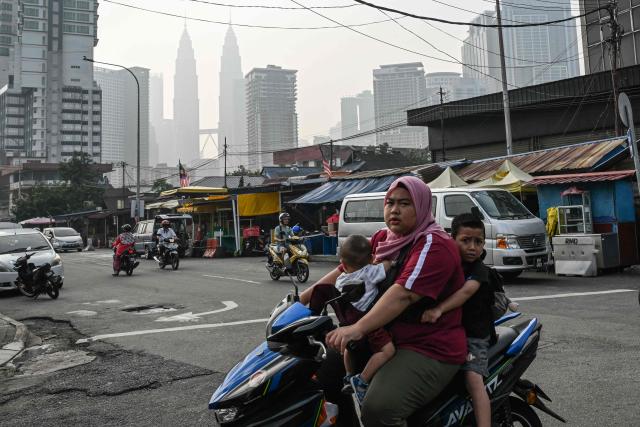 A motorcyclist with young children riding pillion rides past in Kuala Lumpur on October 17, 2026, as the country continues to be shrouded in haze caused by fires in Indonesia. The blazes in Indonesia have closed schools and fuelled a surge of respiratory complaints and growing frustration about the inability to contain the situation. (Photo by Jam STA ROSA / AFP)