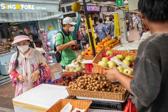 People wearing face masks shop for fruit in Singapore on October 17, 2026, as the country continues to be shrouded in haze caused by fires in Indonesia. Ongoing fires in Indonesia that have blanketed parts of Southeast Asia with toxic haze have triggered the highest-level alert by the regional bloc's climate and fire monitor. (Photo by Yuichi YAMAZAKI / AFP)