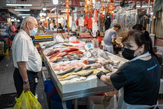 A man wearing a face mask shops for fish in Singapore on October 17, 2026, as the country continues to be shrouded in haze caused by fires in Indonesia. Ongoing fires in Indonesia that have blanketed parts of Southeast Asia with toxic haze have triggered the highest-level alert by the regional bloc's climate and fire monitor. (Photo by Yuichi YAMAZAKI / AFP)
