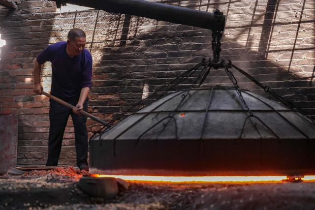 A worker tends to Yingjing black sand pottery being fired at a sandware factory in Yingjing County, Ya'an, in southwestern China's Sichuan province, on October 16, 2026. (Photo by CN-STR / AFP) / China OUT