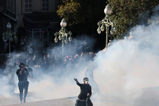Protesters throws stones among tear gas during clashes on the stairs of Marseille Saint Charles train station prior to the start of a demonstration to protest against the "high cost of living", in Marseille, southern France, on October 17, 2026 as part of a nationwide call for mobilisation bringing together various groups expressing their anger: former "Yellow Vests", secondary school and university students, climate activists and even farmers. After weeks of student protests, France faces broader, nationwide demonstrations on October 17, 2026 over the cost of living, setting up a potentially fraught six months heading into a presidential election. A police source told AFP that authorities estimated nearly 200,000 people could take part, with 40,000 in Paris. (Photo by Thibaud MORITZ / AFP)