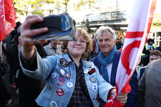 Communist Party (PCF) candidate in France's 2027 presidential election Fabien Roussel (R) poses for a selfie picture as he attends a demonstration to protest against the "high cost of living", in Valenciennes, northern France, on October 17, 2026 as part of a nationwide call for mobilisation bringing together various groups expressing their anger: former "Yellow Vests", secondary school and university students, climate activists and even farmers. After weeks of student protests, France faces broader, nationwide demonstrations on October 17, 2026 over the cost of living, setting up a potentially fraught six months heading into a presidential election. A police source told AFP that authorities estimated nearly 200,000 people could take part, with 40,000 in Paris. (Photo by Sameer AL-DOUMY / AFP)