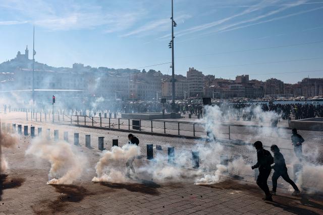 Protesters move through a cloud of tear gas during a demonstration against the "high cost of living", in Marseille, southern France, on October 17, 2026 as part of a nationwide call for mobilisation bringing together various groups expressing their anger: former "Yellow Vests", secondary school and university students, climate activists and even farmers. After weeks of student protests, France faces broader, nationwide demonstrations on October 17, 2026 over the cost of living, setting up a potentially fraught six months heading into a presidential election. A police source told AFP that authorities estimated nearly 200,000 people could take part, with 40,000 in Paris. (Photo by Thibaud MORITZ / AFP)
