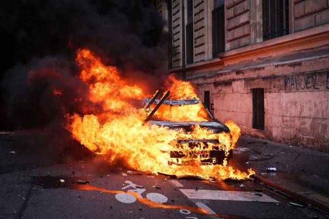 Flames ravage a car during a demonstration to protest against the "high cost of living", in Paris on October 17, 2026 as part of a nationwide call for mobilisation bringing together various groups expressing their anger: former "Yellow Vests", secondary school and university students, climate activists and even farmers. After weeks of student protests, France faces broader, nationwide demonstrations on October 17, 2026 over the cost of living, setting up a potentially fraught six months heading into a presidential election. A police source told AFP that authorities estimated nearly 200,000 people could take part, with 40,000 in Paris. (Photo by Kiran RIDLEY / AFP)