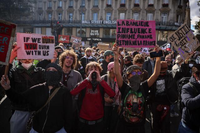 Protesters hold placards reading "The suburbs influence Paris, Paris returns France" during a demonstration to protest against the "high cost of living", at Place de la Republique in Paris on October 17, 2026 as part of a nationwide call for mobilisation bringing together various groups expressing their anger: former "Yellow Vests", secondary school and university students, climate activists and even farmers. After weeks of student protests, France faces broader, nationwide demonstrations on October 17, 2026 over the cost of living, setting up a potentially fraught six months heading into a presidential election. A police source told AFP that authorities estimated nearly 200,000 people could take part, with 40,000 in Paris. (Photo by Kiran RIDLEY / AFP)